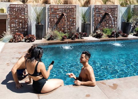 Friends enjoying leisure time by a scenic poolside surrounded by lush greenery in summer.